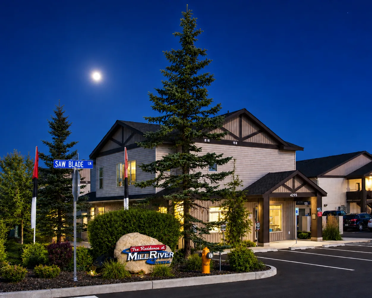 A building under a night sky with a full moon, a pine tree, and a sign reading 